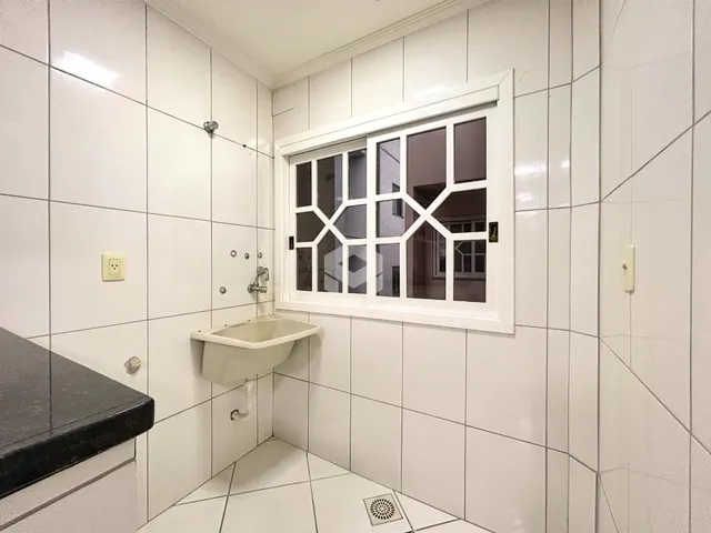 Foto de um banheiro com revestimento cerâmico branco e janela.