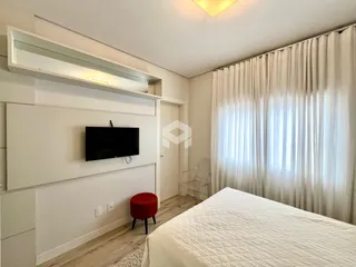 Quarto com cama e televisão em ambiente claro.