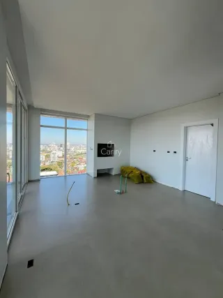 Vista ampla de um ambiente interno com grandes janelas que oferecem uma vista da cidade.
