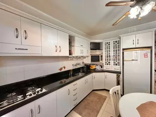 Foto de uma cozinha com armários brancos e bancadas escuras.