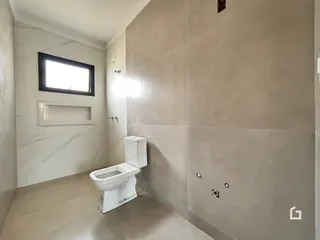 Foto de um banheiro com paredes claras e piso de tom neutro.
