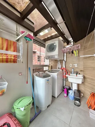 Foto de uma área de serviço com máquinas de lavar e pia em uma residência.