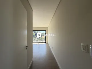 Foto de um corredor interno com paredes brancas e piso claro.