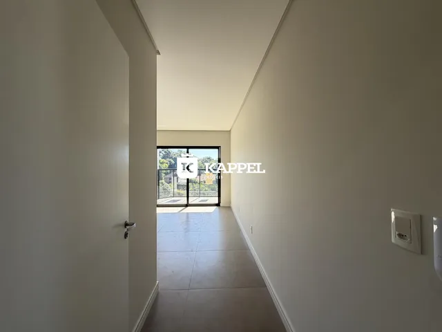 Foto de um corredor interno com paredes brancas e piso claro.