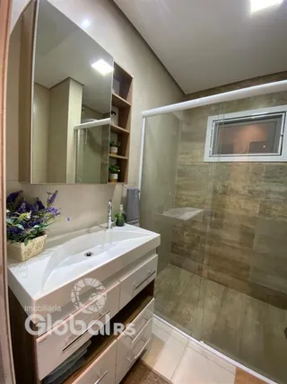 Foto de um banheiro com box de vidro e bancada de madeira.