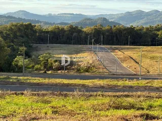Paisagem rural com colinas e vegetação ao fundo.