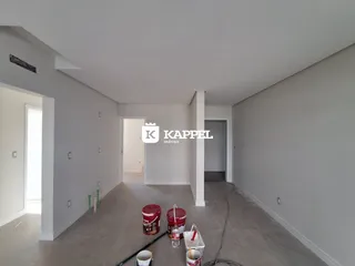Hall de entrada com paredes brancas e piso de concreto em um imóvel.