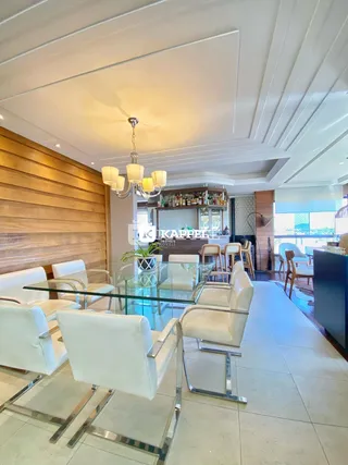Sala de estar com assentos brancos e mesa de vidro em um ambiente com painéis de madeira.