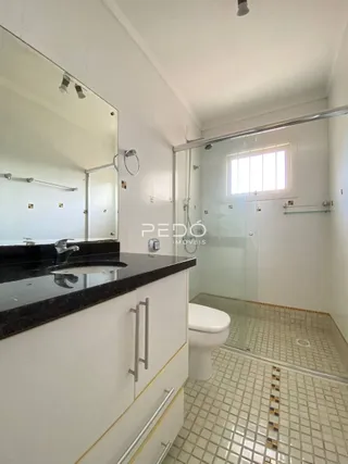 A foto mostra o interior de um banheiro com box de vidro e piso de cerâmica.