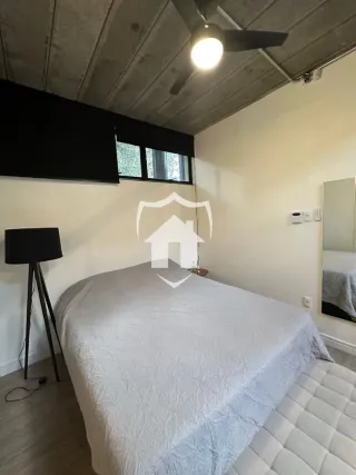 Quarto com cama grande e teto de concreto.