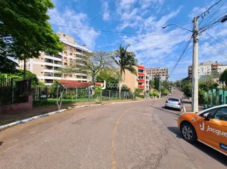Vista da rua em Lajeado, Brasil, com árvores e casas ao fundo.