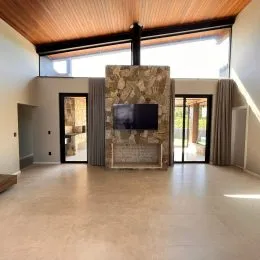 Sala de estar com teto de madeira e parede de pedra aparente.