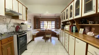 Ambiente de cozinha e jantar com armários de madeira e piso de cerâmica.