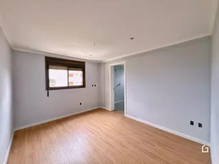 Ambiente interno de uma sala com piso de madeira clara e paredes cinzas.