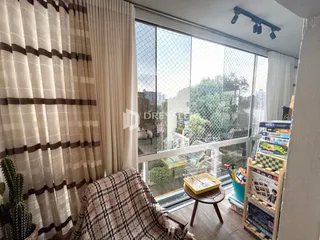 Vista da sala com cortinas claras e grandes janelas.
