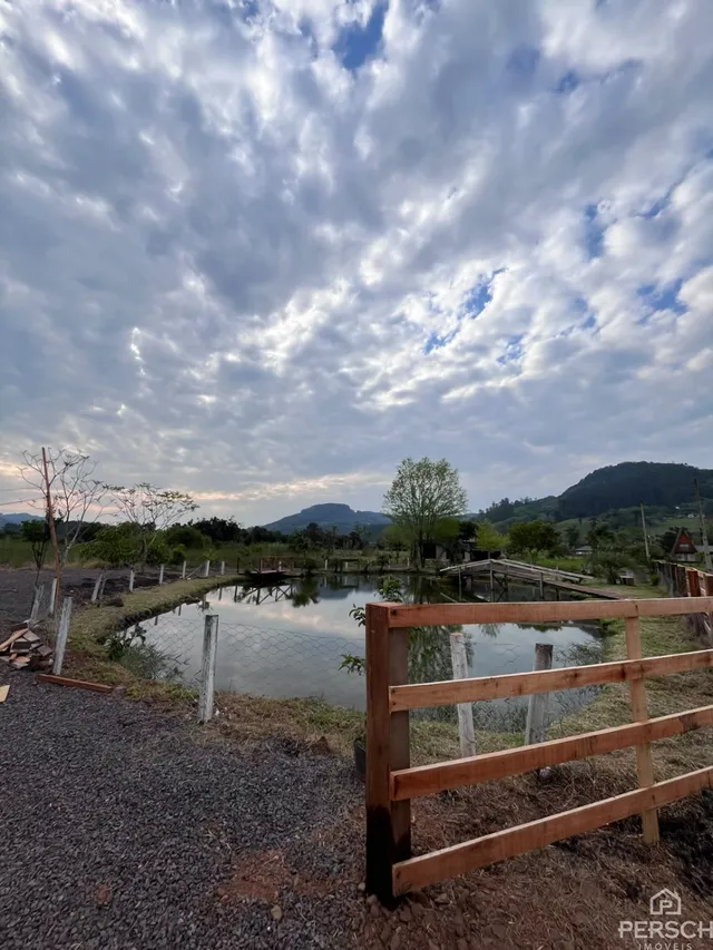 Foto externa mostrando um lago e vegetação em uma paisagem rural.