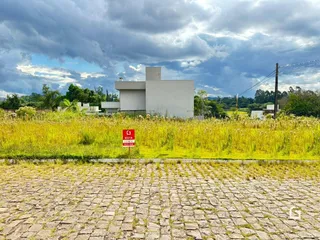 Vista externa de uma residência em Lajeado, Brasil, cercada por grama alta e uma área pavimentada.