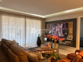 Sala de estar com sofá e janela com cortinas claras.
