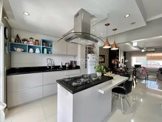 Esta é uma foto de uma cozinha moderna com armários brancos e bancadas escuras.