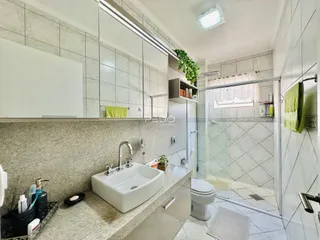 Foto de um banheiro com box de vidro e revestimento cerâmico.