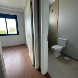 Hall de entrada com piso de madeira e portas brancas.