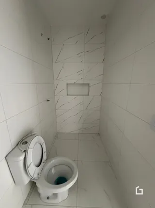 Foto de um banheiro com revestimento de azulejos brancos.