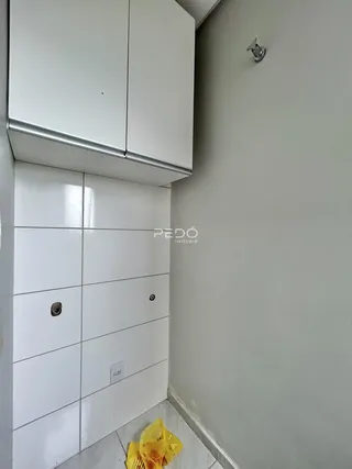 Parede com revestimento cerâmico branco e armários superiores em um ambiente interno.