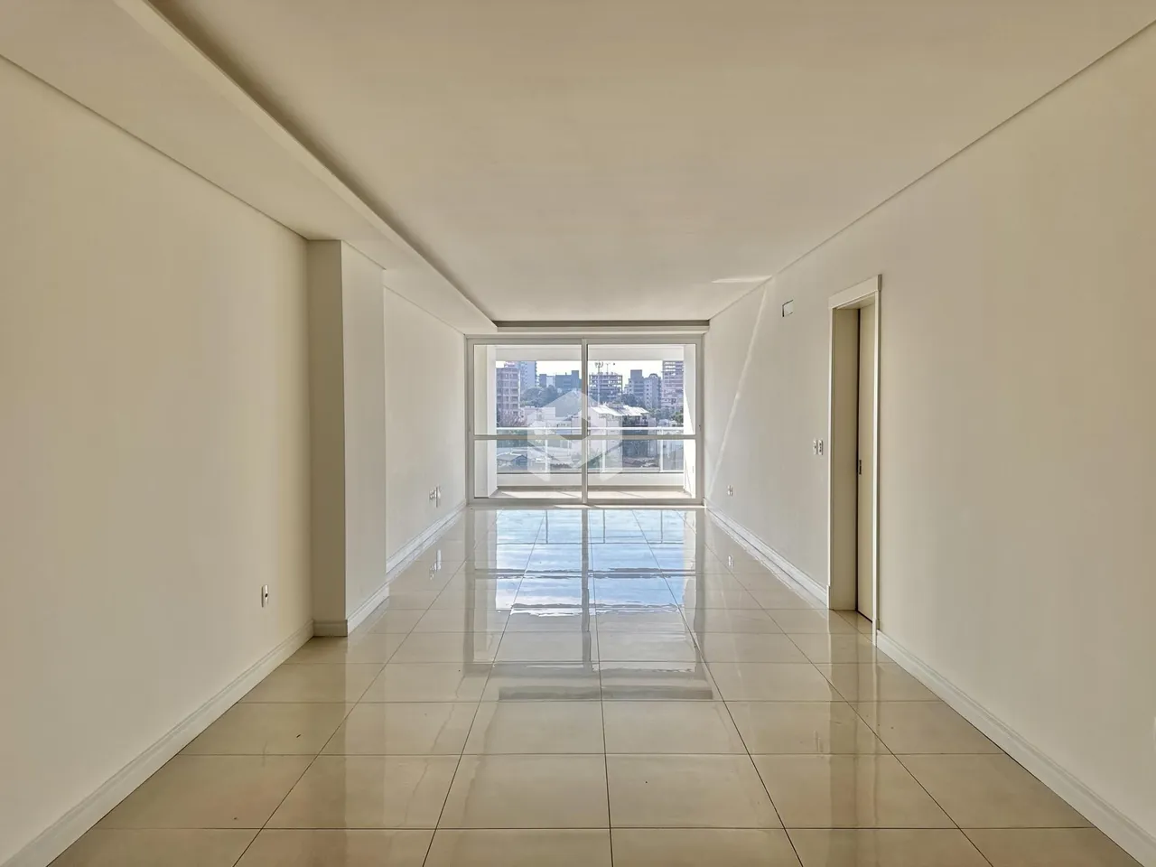 Corredor interno de um imóvel com piso de cerâmica e grande janela.