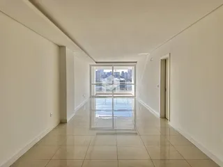 Corredor interno de um imóvel com piso de cerâmica e grande janela.