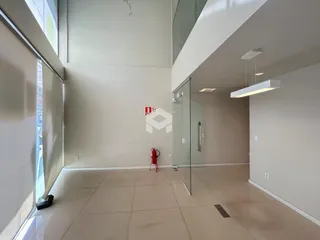Ambiente interno de uma sala de estar com piso de cerâmica e divisória de vidro.