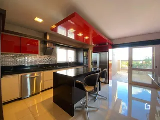 Vista da cozinha moderna com armários vermelhos e bancada escura.