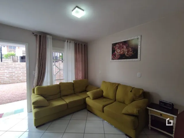 Sala de estar com sofá amarelo e piso de cerâmica.