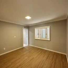 Foto de um ambiente interno com piso de madeira clara e paredes neutras.