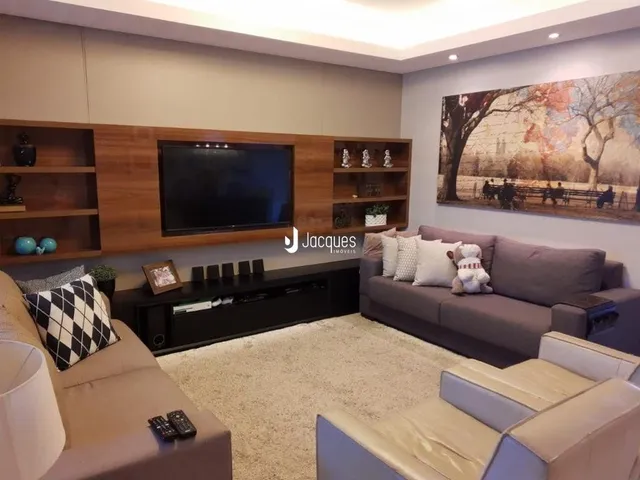 Sala de estar com sofá e televisão em um imóvel.