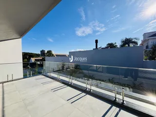 Vista de uma varanda moderna com piso claro e grade de vidro.