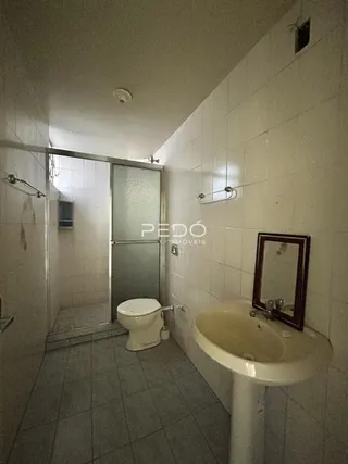Foto de um banheiro com azulejos brancos e louças sanitárias.