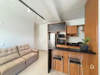 Sala de estar com sofá e cozinha integrada em apartamento.