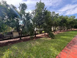 Vista externa do terreno com gramado e vegetação ao redor.