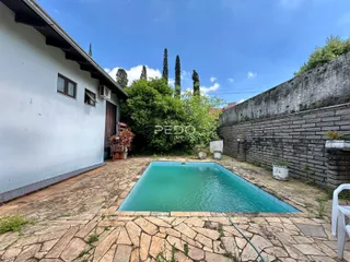 Vista externa de uma propriedade com piscina e muro de tijolos.