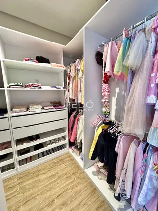 Interior com estantes brancas e roupas penduradas em um ambiente claro.