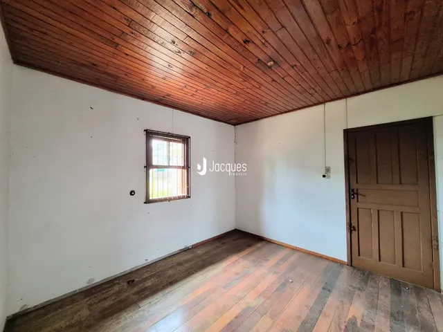 Ambiente interno de uma sala com piso de madeira e teto de tábuas de madeira.