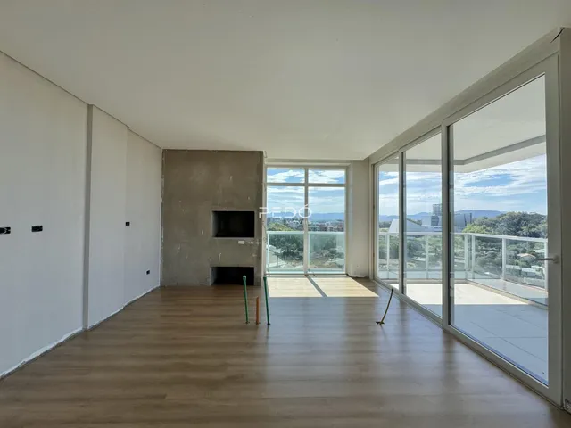 Sala de estar com piso de madeira e grandes janelas de vidro.