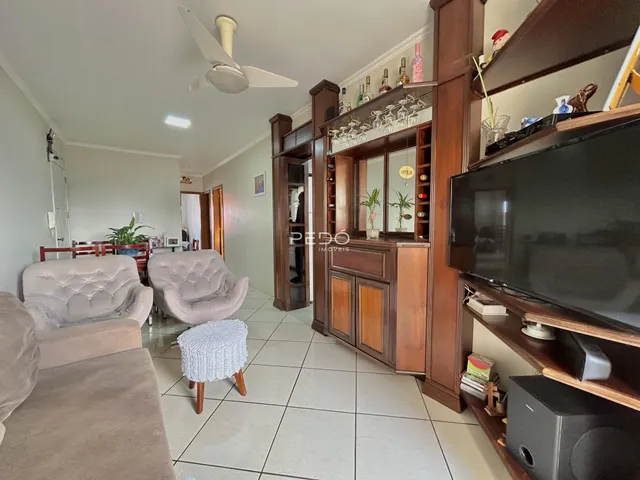 Sala de estar com sofás e móveis de madeira em um imóvel em Lajeado.