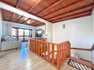 Sala de estar com piso de madeira e teto de madeira no imóvel em Lajeado.