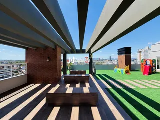 Vista de uma área externa com deck de madeira e gramado verde.