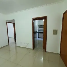 Hall de entrada com paredes brancas e porta de madeira.