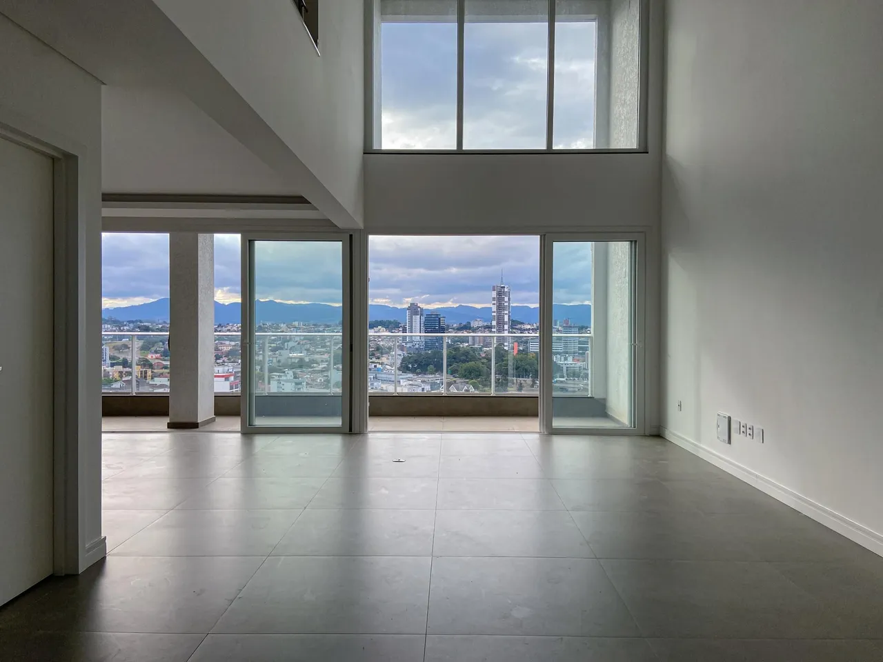 Sala ampla com grandes janelas oferecendo uma vista panorâmica da cidade.