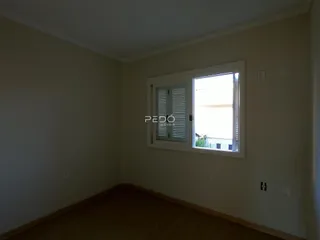 Vista interna de um cômodo com paredes claras e piso de madeira.