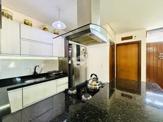 Cozinha moderna com armários brancos e bancadas escuras.