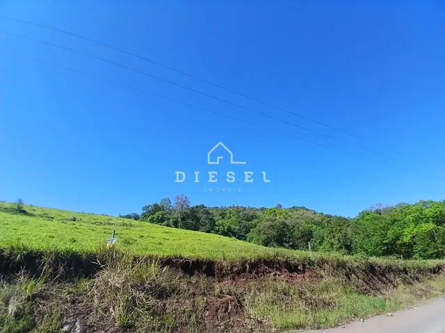 Paisagem de colinas verdes e vegetação densa sob um céu azul.